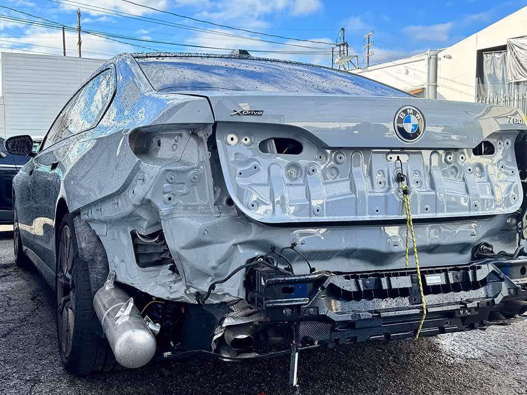 Silver BMW 7 Series with extensive rear-end damage, missing bumper and tail lights.