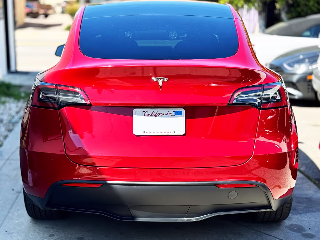 Rear view of a shiny red Tesla Model Y parked on a street with Texas license plate.